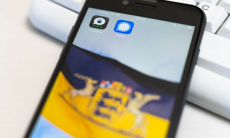 Ein Smartphone auf dessen Display eine Baden-Württemberg-Fahne und die Apps Threema und Signal zu sehen sind.