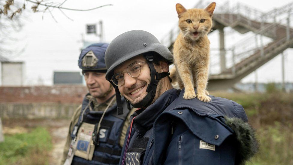 Soldin lächelt in die Kamera, während ihm während eines Einsatzes für AFP in der Ukraine eine Katze auf den Schultern steht