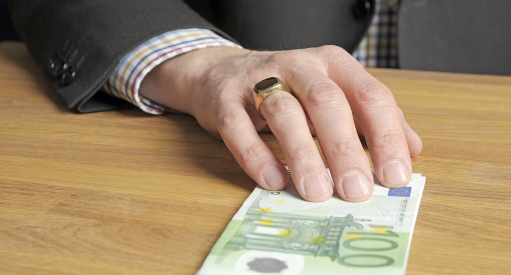 Eine Hand schiebt Geldscheine über den Tisch.  Quelle: www.polizei-beratung.de Eine Hand schiebt Geldscheine über den Tisch.