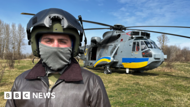 Ukrainian pilot Vasil, pictured with his face covered in front of a Sea King helicopter donated by the UK and painted with the blue and yellow stripes of the Ukrainian flag.