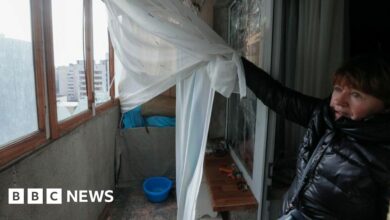 A woman shows the broken windows on her balcony after a rocket strike in Kyiv, 09 March 2023