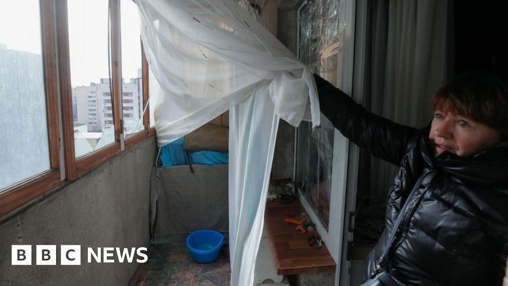 A woman shows the broken windows on her balcony after a rocket strike in Kyiv, 09 March 2023