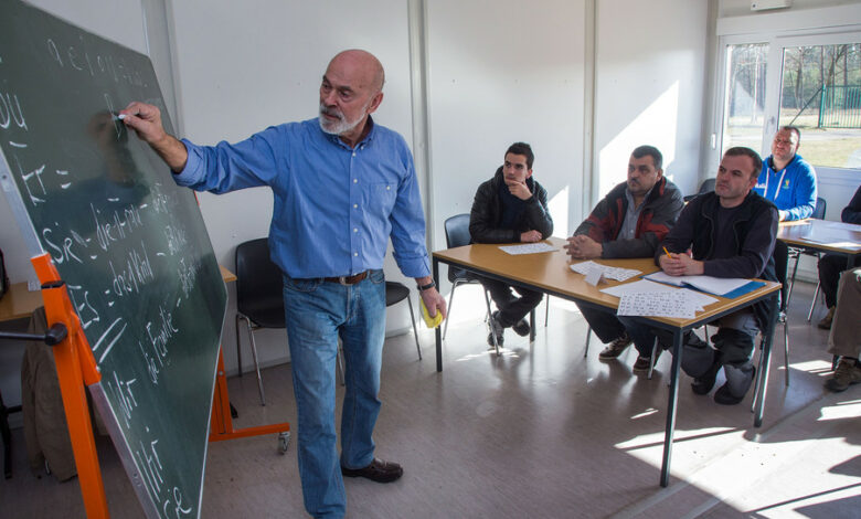 Ein Lehrer schreibt vor Asylbewerbern deutsche Vokabeln an eine Schultafel. (Foto: Jens Büttner/dpa)