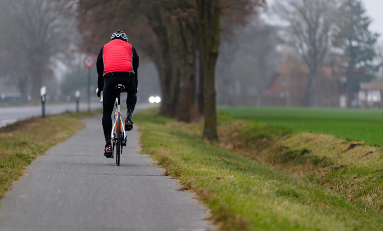 Ein Radfahrer fährt an einer Landstraße entlang.