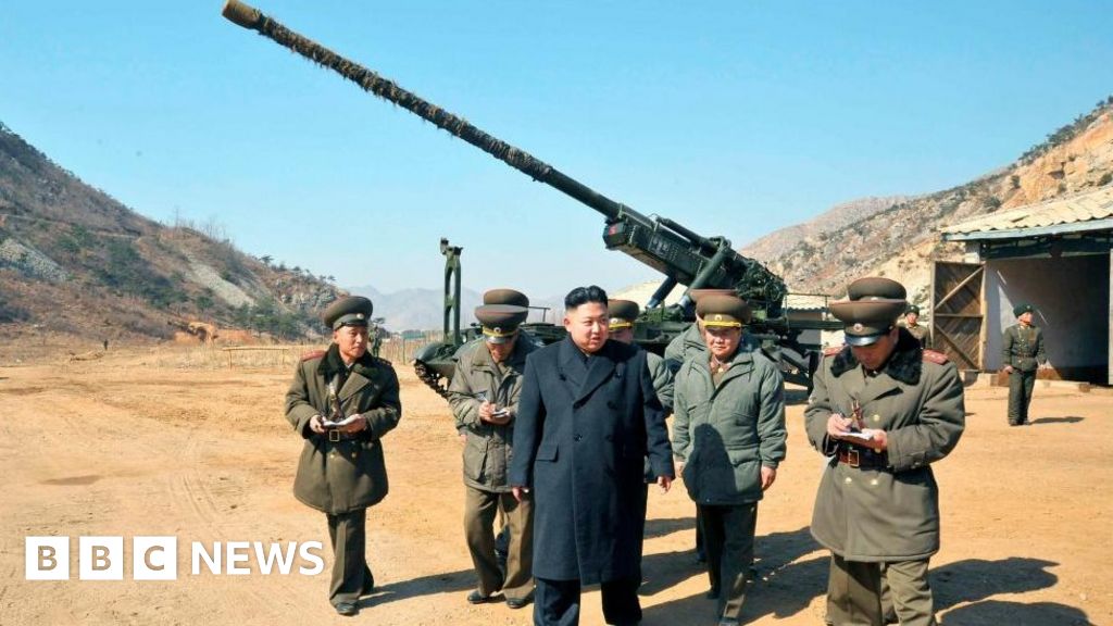 North Korean leader Kim Jong-Un stands in front of a long-range artillery with other officials