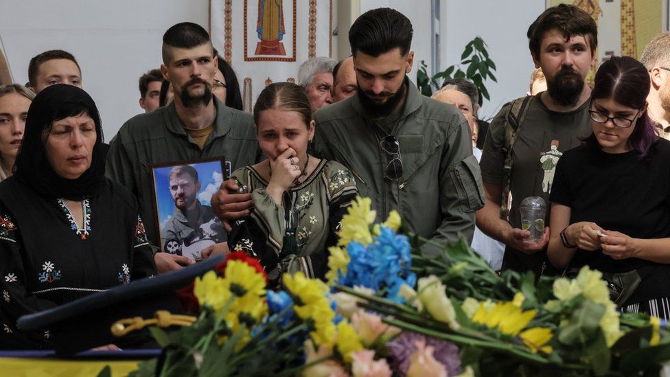 Ein Mann hält ein Foto des ukrainischen Kampfpiloten Andriy Pilshchykov während seiner Trauerfeier in einer Kathedrale in Kiew. Foto: 29. August 2023