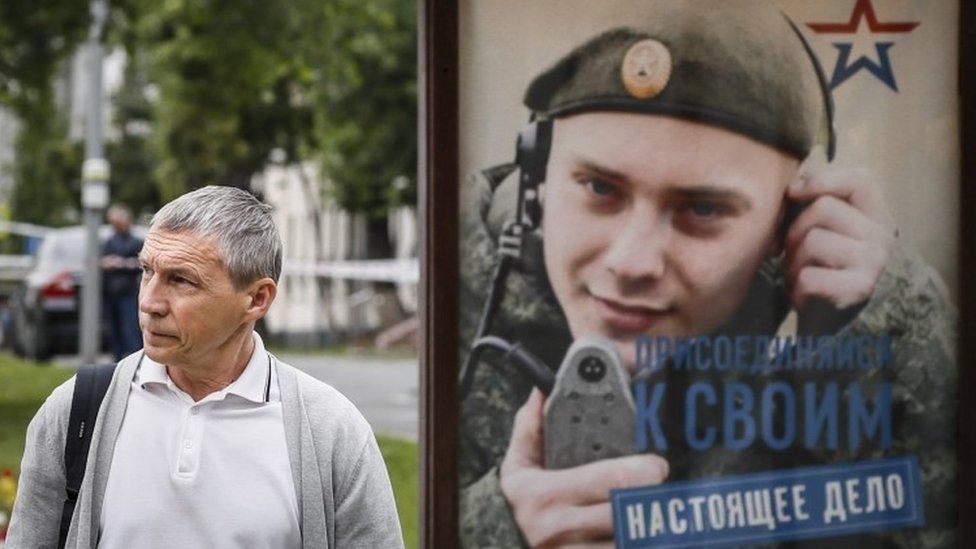 Ein Mann geht an einer Bushaltestelle in Moskau an einem Wehrpflichtplakat vorbei
