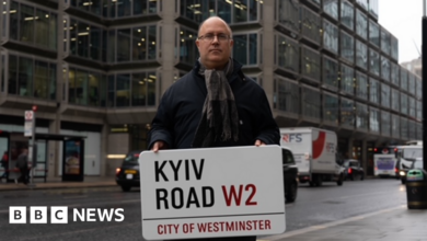 Councillor Adam Hug holds up a Kyiv Road sign