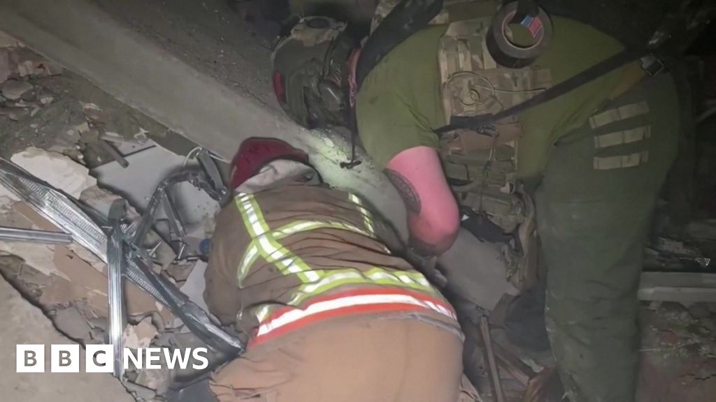 Screengrab of footage that shows rescuers in Ukraine looking through a smoking, ruined building