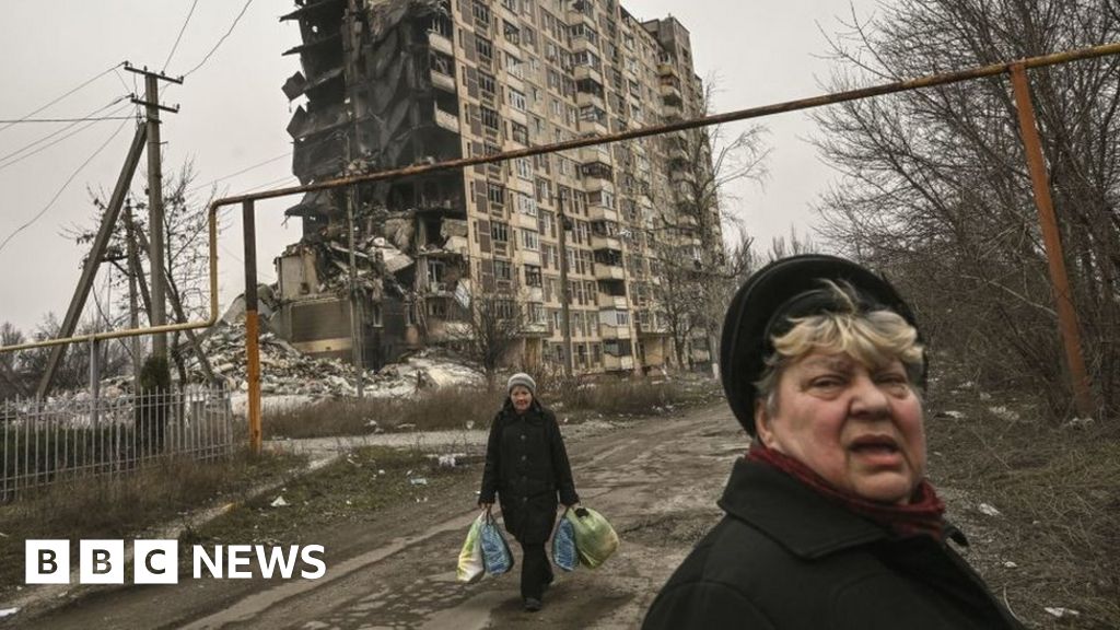 An elderly woman walks in front of a destroyed apartment building in the city of Avdiivka in Ukraine.