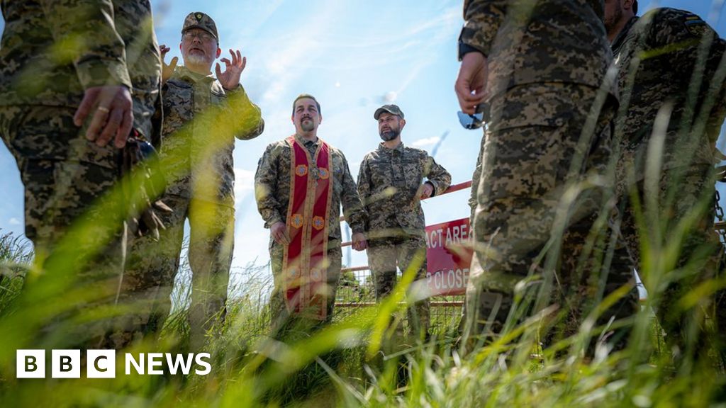 Ukrainian military chaplains talk with each other on the range area as several chaplains complete their training alongside Ukrainian soldiers and British Army training staff at a camp close to Warminster, Wiltshire.